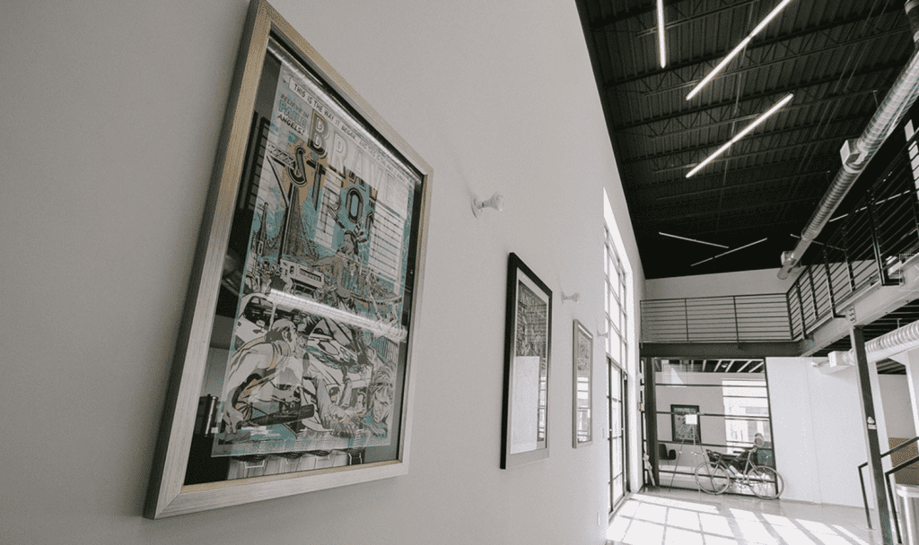 Modern art gallery in Louisville with framed illustrations, high ceilings, and large windows by Eldridge Company, top custom home builder.